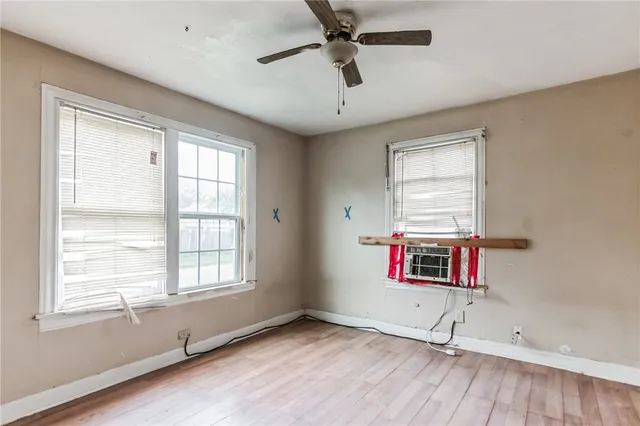 a view of an empty room with a window and wooden floor