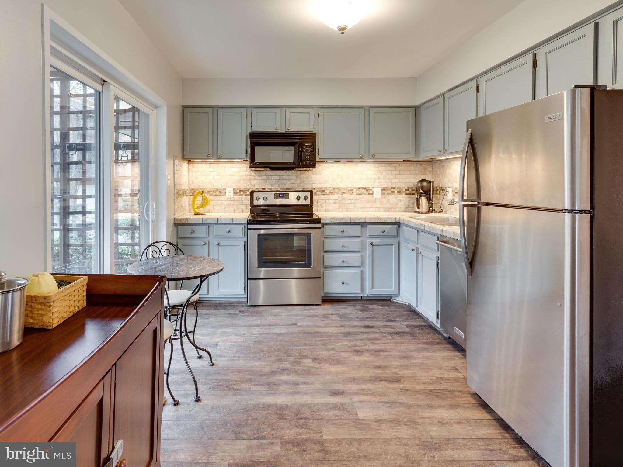 1663 Bachan Court Reston, VA 20190 - Photo 4 of 29 a kitchen with stainless steel appliances granite countertop a refrigerator a stove top oven a sink dishwasher and white cabinets with wooden floor