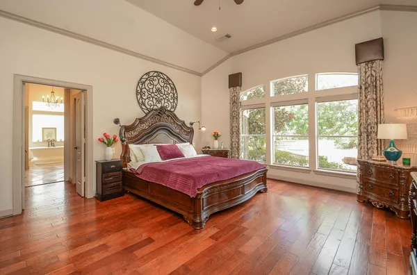 a spacious bedroom with a bed and wooden floor