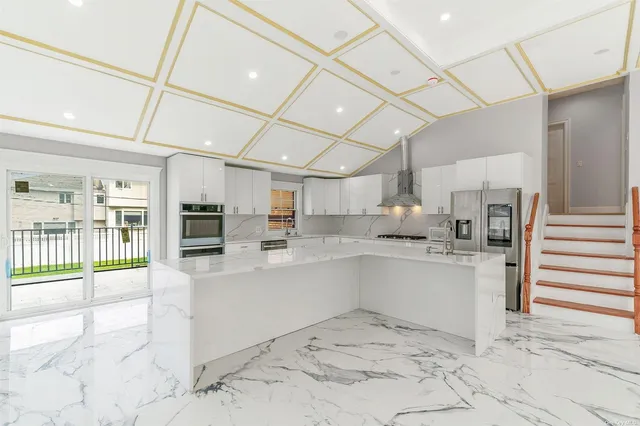 a room with stainless steel appliances kitchen island granite countertop a refrigerator and a sink