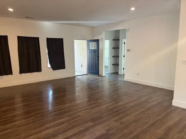 a view of an empty room with wooden floor and windows