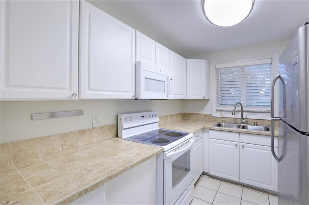 1010 Manatee Road, Unit B101 Naples, FL 34114 - Photo 9 of 26 a kitchen with white cabinets and sink