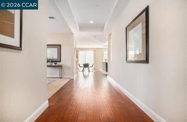 a hallway with wooden floor windows and chandelier