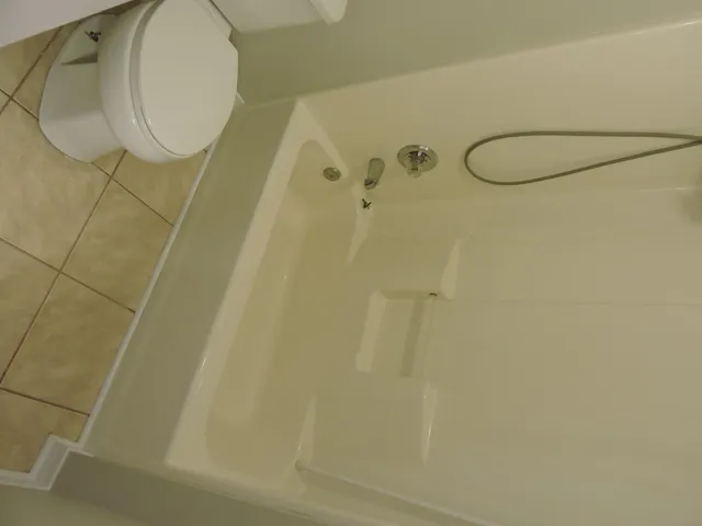 an empty room with a chandelier fan and wooden floor