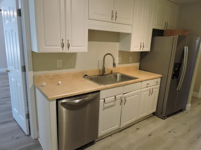 a kitchen with stainless steel appliances granite countertop white cabinets a refrigerator and a sink