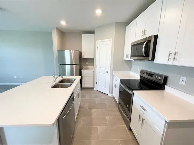 a kitchen with a sink a counter top space stainless steel appliances and cabinets