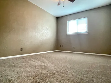 an empty room with windows and chandelier fan