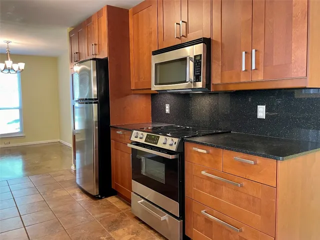 a kitchen with granite countertop a refrigerator stove and microwave