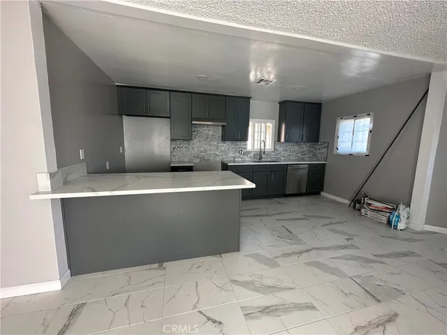 a room with kitchen island a sink a stove and a chandelier