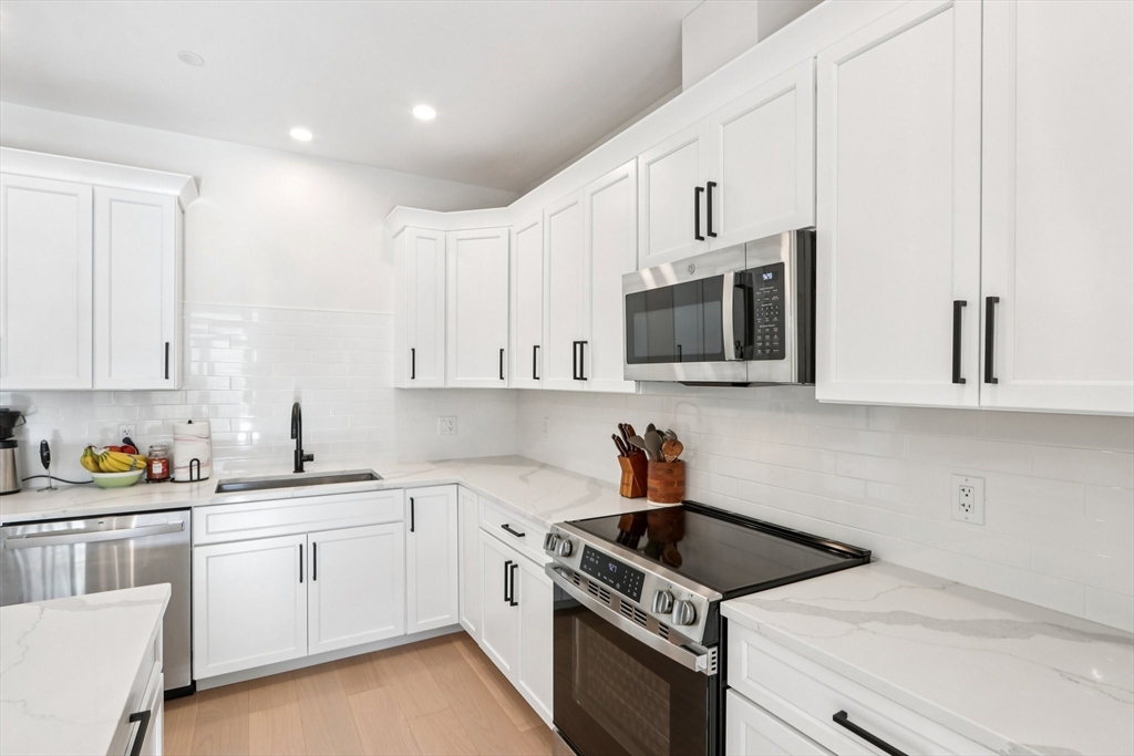 62 Foundry Street, Unit 204 Wakefield, MA 01880 - Photo 9 of 28 a kitchen with white cabinets a sink stove and microwave