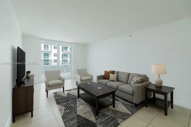 a living room with furniture a flat screen tv and a window