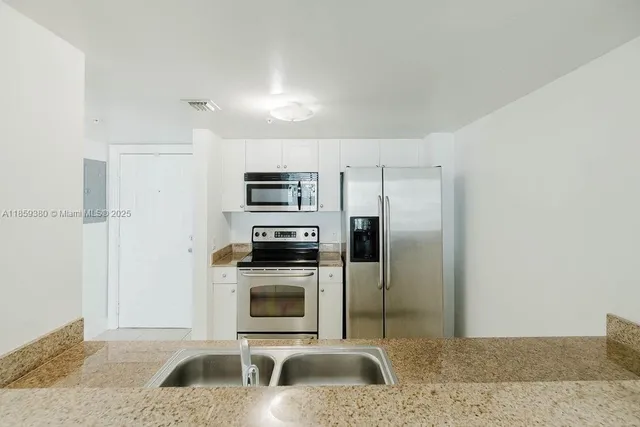 a kitchen with stainless steel appliances granite countertop a refrigerator sink and stove
