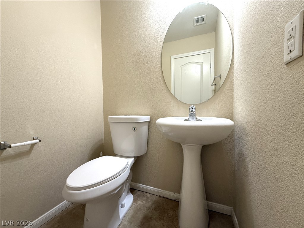 5942 Rampolla Drive Las Vegas, NV 89141 - Photo 10 of 27 A compact and functional bathroom space featuring a pristine pedestal sink and a contemporary toilet.