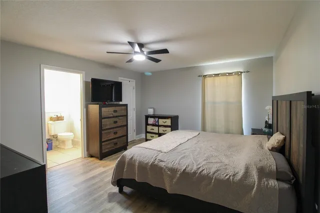 a spacious bedroom with a bed and a flat screen tv