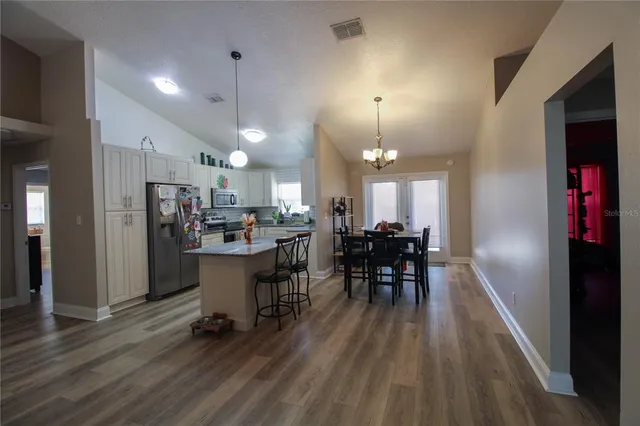 a kitchen with a dining table chairs refrigerator and cabinets