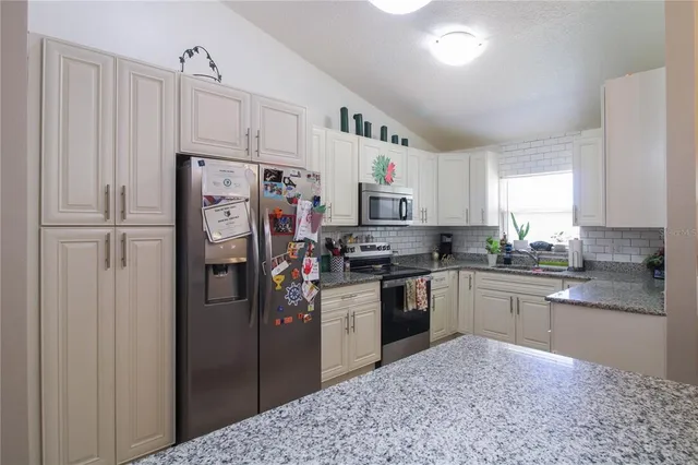a kitchen with stainless steel appliances granite countertop a refrigerator stove and sink