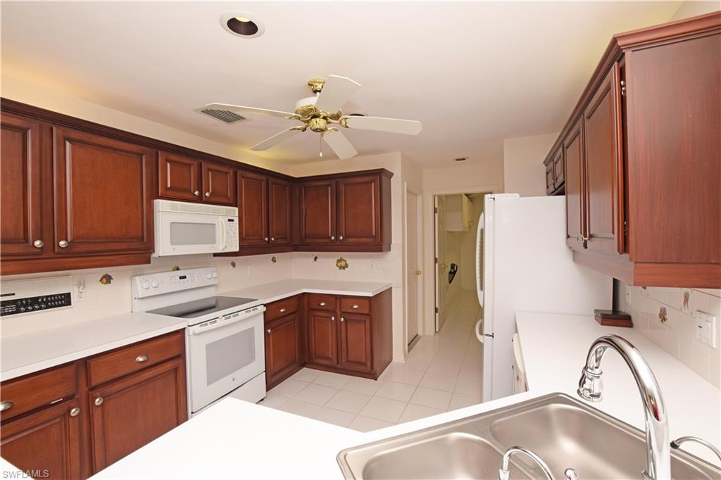107 Napa Ridge Way Naples, FL 34119 - Photo 13 of 26 a kitchen with a sink a stove a refrigerator and cabinets
