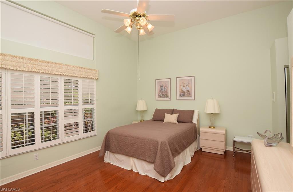 107 Napa Ridge Way Naples, FL 34119 - Photo 17 of 26 a bedroom with a large bed chandelier and a window