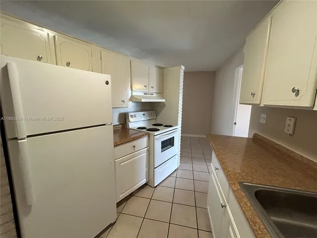 a kitchen with a refrigerator sink and cabinets
