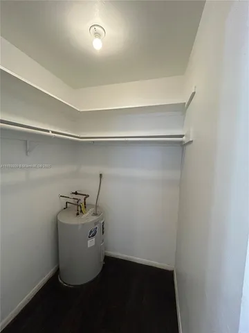 a room with water heater and wooden cabinets