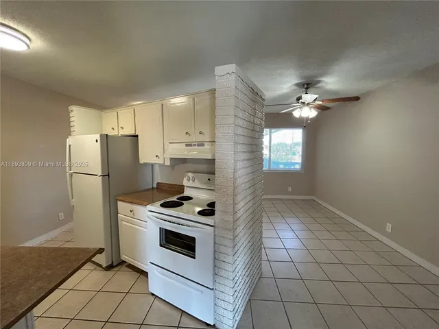 a kitchen with a stove a refrigerator and white cabinets