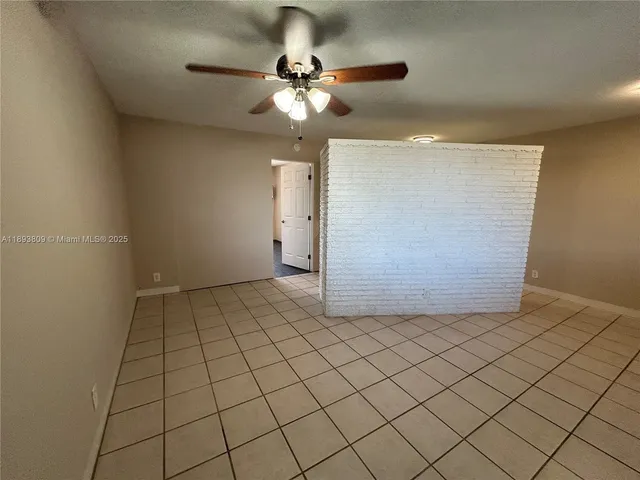 a view of an empty room and chandelier fan