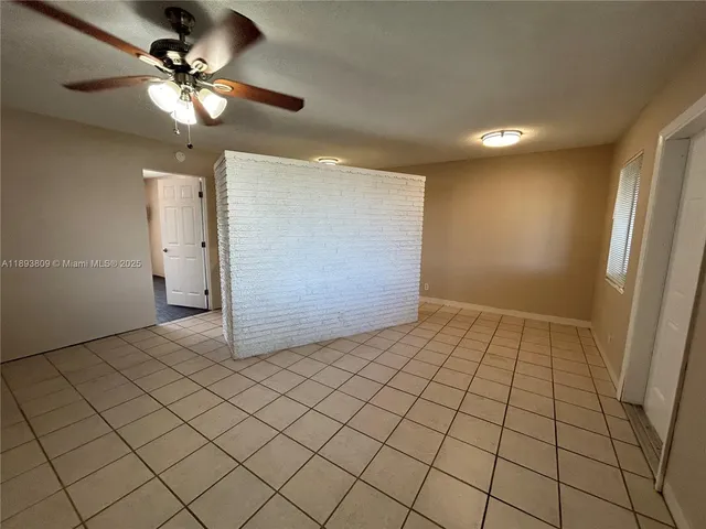 a view of an empty room and chandelier fan