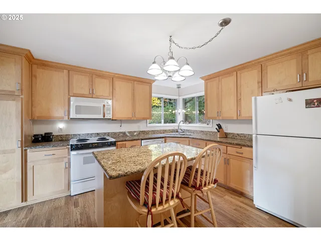 a kitchen with granite countertop a stove a sink dishwasher a refrigerator with white cabinets and wooden floor