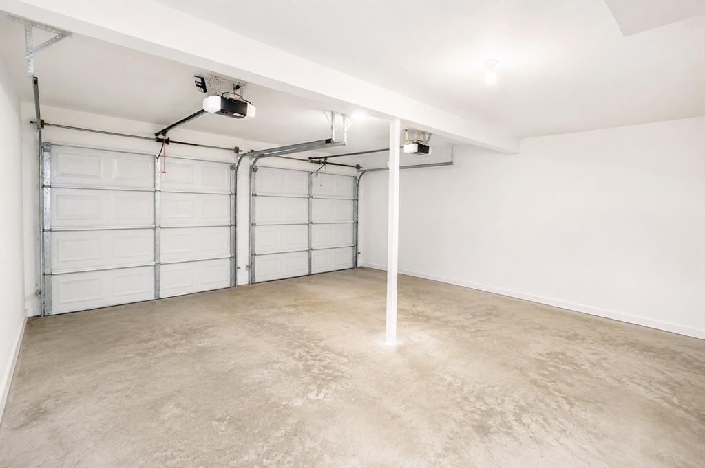 6545 Los Rios Drive Mesquite, TX 75150 - Photo 7 of 9 Spacious garage featuring two overhead doors, automatic openers, a concrete floor, painted white walls, and an exposed support beam