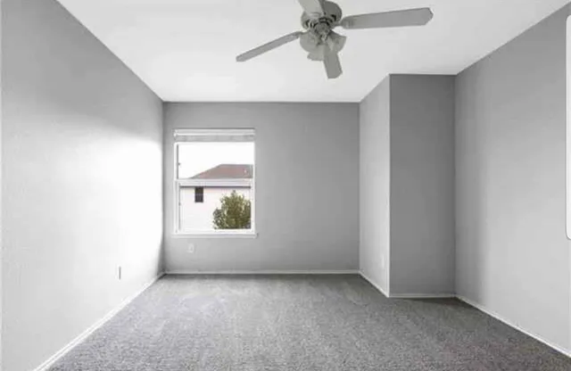 an empty room with a window and a fan