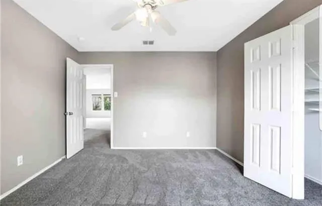 a view of an empty room and chandelier fan