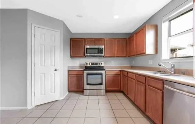 a kitchen with stainless steel appliances granite countertop a stove top oven a sink a counter top space and cabinets