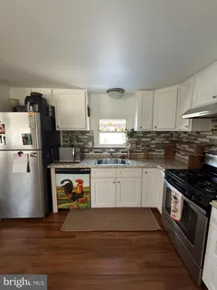 a kitchen with granite countertop a refrigerator stove and sink