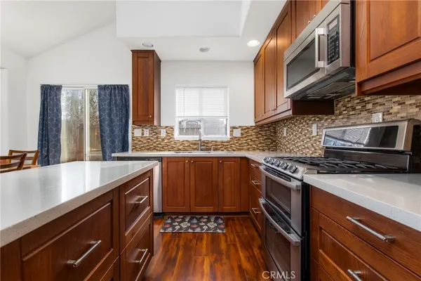 a kitchen with stainless steel appliances granite countertop a stove a sink and a microwave