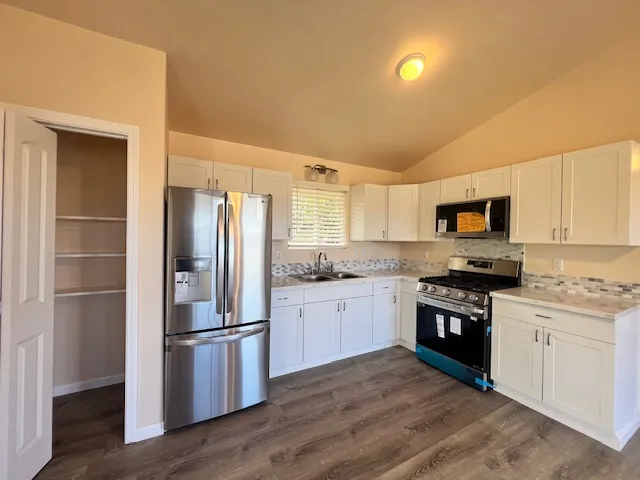 a kitchen with stainless steel appliances granite countertop a refrigerator stove and sink