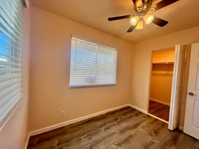 a view of empty room with wooden floor and fan