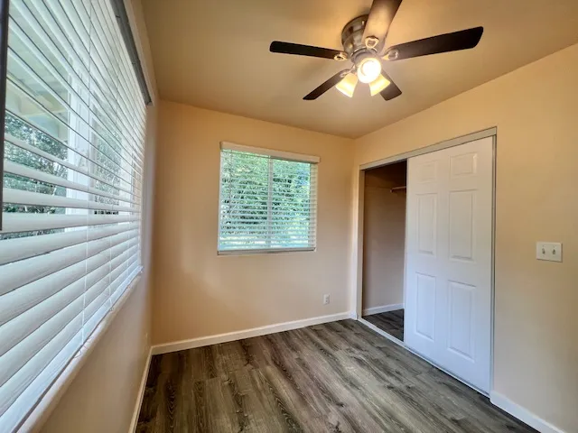 a view of empty room with wooden floor and fan