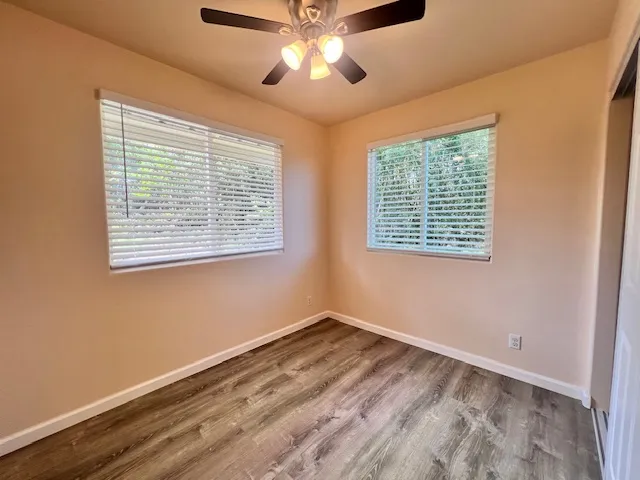 a view of an empty room with a window and a chandelier fan