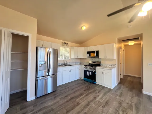 a kitchen with granite countertop a refrigerator and a stove top oven