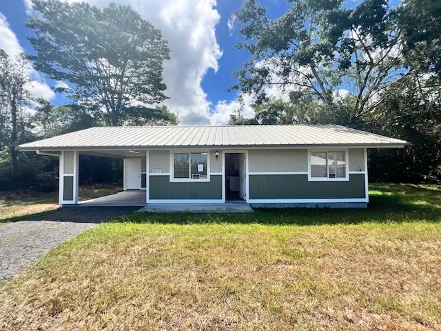 a front view of a house with a garden and trees