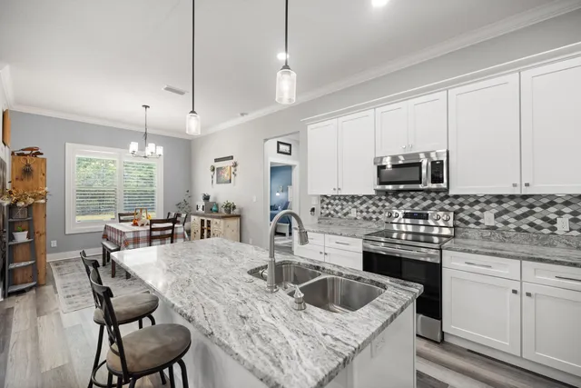 a kitchen with granite countertop a stove refrigerator dining table and chairs
