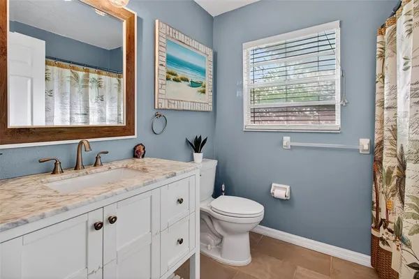 a bathroom with a granite countertop toilet a sink a mirror and a window