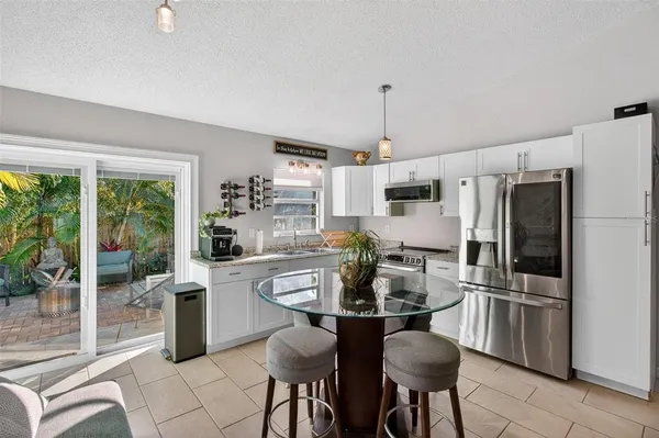 a kitchen with granite countertop a table chairs microwave and refrigerator
