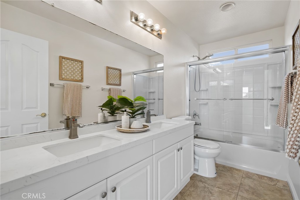 6124 Risingstar Drive Eastvale, CA 92880 - Photo 34 of 37 a bathroom with a double vanity sink toilet and shower