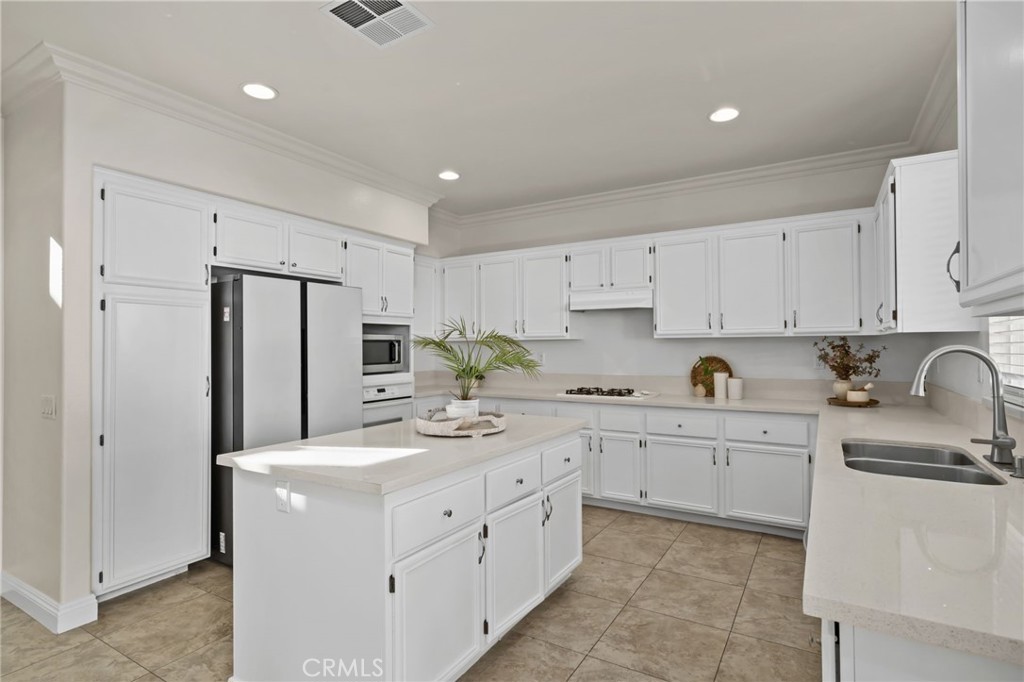 6124 Risingstar Drive Eastvale, CA 92880 - Photo 10 of 37 a kitchen with white cabinets stainless steel appliances and sink