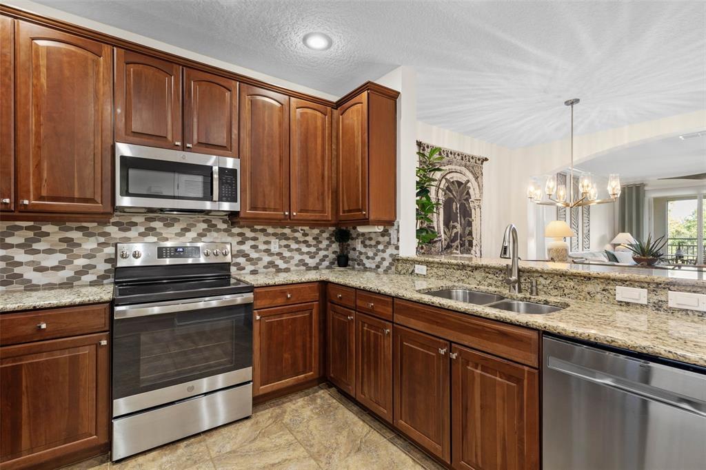 55 Riverview Bend South, Unit 2033 Palm Coast, FL 32137 - Photo 21 of 75 a kitchen with granite countertop wooden cabinets and stainless steel appliances