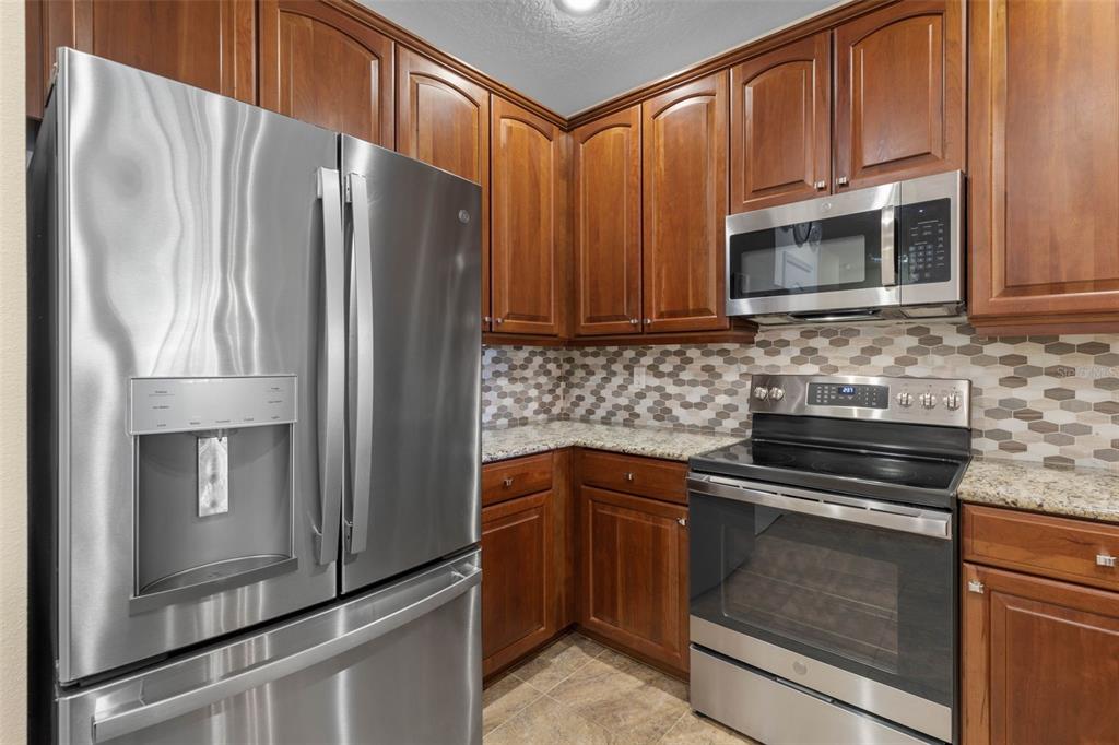 55 Riverview Bend South, Unit 2033 Palm Coast, FL 32137 - Photo 22 of 75 a kitchen with granite countertop a refrigerator stove and microwave