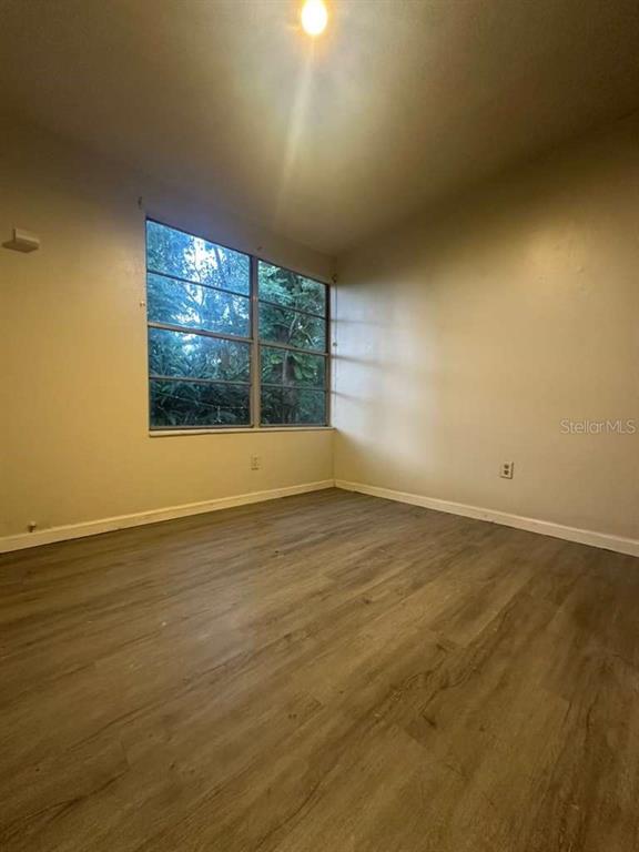 322 North Wekiwa Springs Road, Unit B Apopka, FL 32703 - Photo 12 of 15 an empty room with wooden floor and windows
