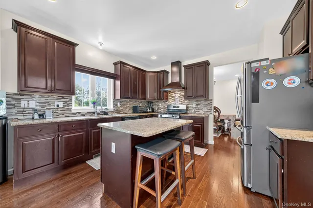 a kitchen with stainless steel appliances kitchen island granite countertop wooden floors and wooden cabinets