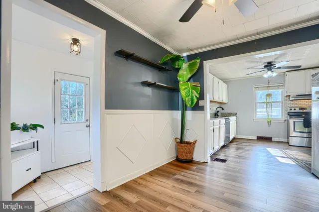a view of a hallway to room with wooden floor and windows
